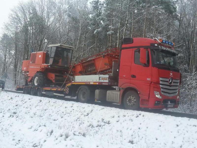 Samochód ciężarowy z koparką na tle drzew